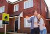 Happy couple in front of recently bought house