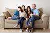 Photo of a family sitting   together in a living room  or any other room of a house.
