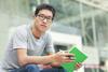 Asian young male wearing glasses and holding a book