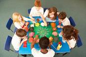 Photo of children in a classroom working in groups or pairs.