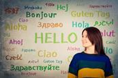girl in front of a blackboard written with the word hello in different languages and colors