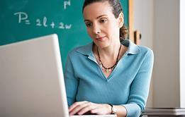 Photo of a teacher writing a paper or typing on their computer.
