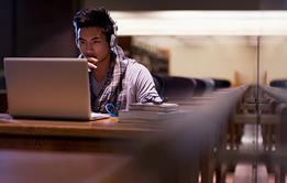Photo of of a student using their mobile phone or at their laptop, looking something up on the internet.