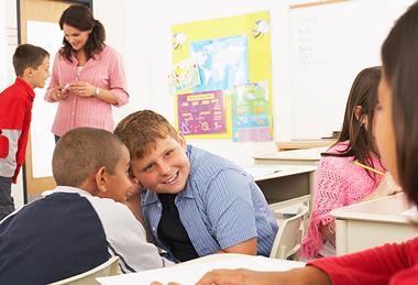 Photo of children speaking to each  other in a classroom.
