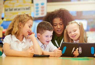 Photo of children and their teacher  working together in a classroom.