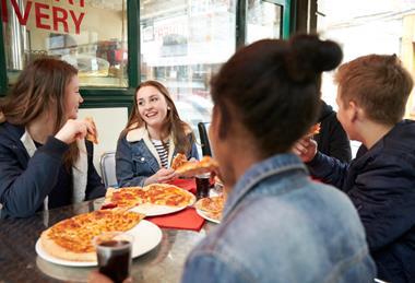 Group of teenagers eating pizza