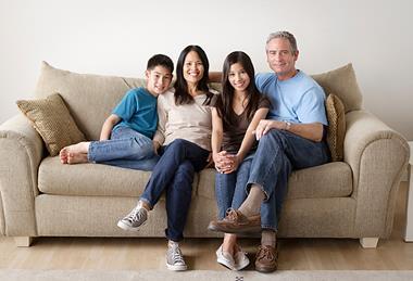 Photo of a family sitting   together in a living room  or any other room of a house.