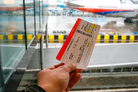 Hand holding plane ticket at airport.