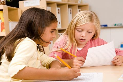 Photo of children writing in their notebook  or typing on a computer.