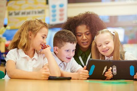 Photo of children and their teacher  working together in a classroom.