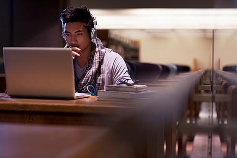 Photo of of a student using their mobile phone or at their laptop, looking something up on the internet.