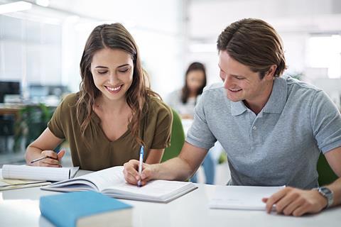 Photo of students writing together in the classroom or even a library.