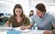 Photo of students writing together in the classroom or even a library.